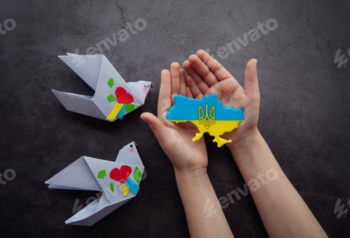 Preview: Hands holding the shape of Ukraine border with color flag