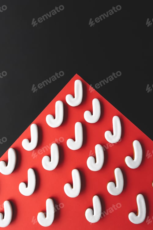 Preview: A lot of gingerbread candy cane shaped cookies on a red background.