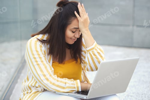 Preview: Lifestyle urban portrait of overweight female freelancer typing on a computer in the park outdoors