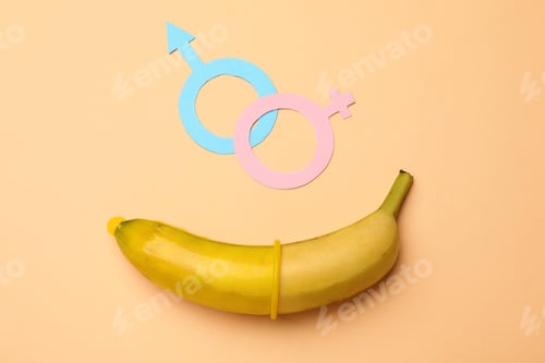 Preview: Sex education. Banana with condom and gender symbols on beige background, flat lay