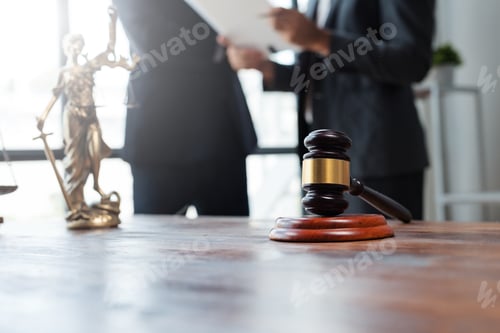 Preview: Gavel, scales of justice, and lawyers discussing legal documents