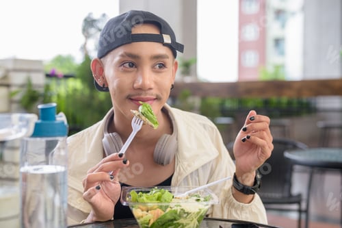 Preview: Nonbinary person eating healthy caesar salad outdoors