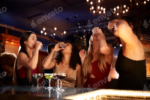 Preview: Group Of Female Friends Drinking Shots In Cocktail Bar Together