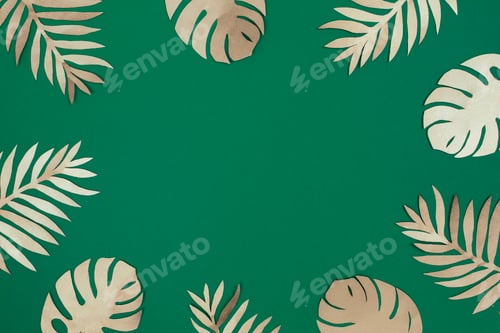 Preview: Tropical gold paper leaves on green background. Top view, flat lay.