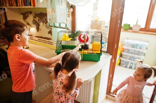 Preview: Children Admiring a Pet Hamster in Cage Indoors