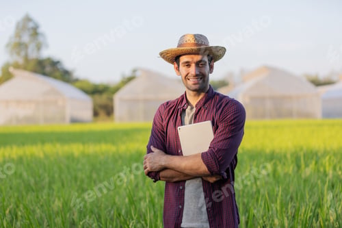 Preview: Confident Farmer Standing in a Lush Green Field with Tablet