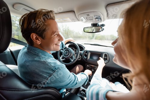 Preview: Selective focus of woman pointing with finger near husband driving car