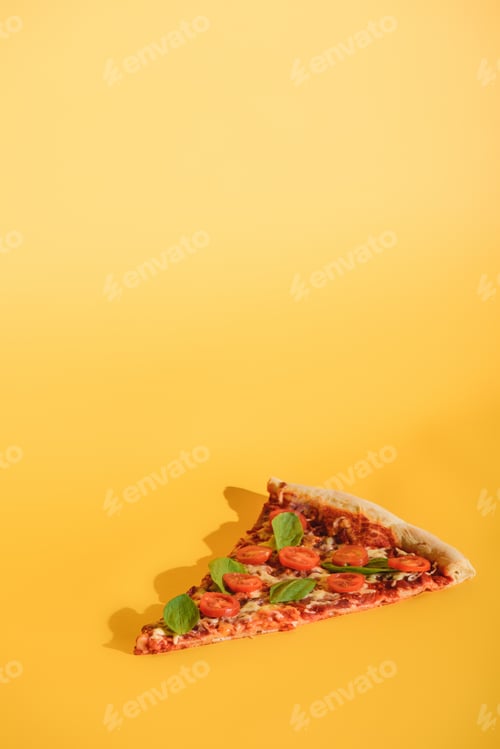 Preview: close up view of piece of pizza with cherry tomatoes and basil on orange backdrop