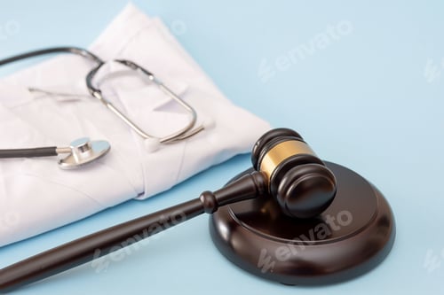 Preview: Stethoscope on folded doctor's lab coat and Gavel on Blue Background for Healthcare Law Concepts