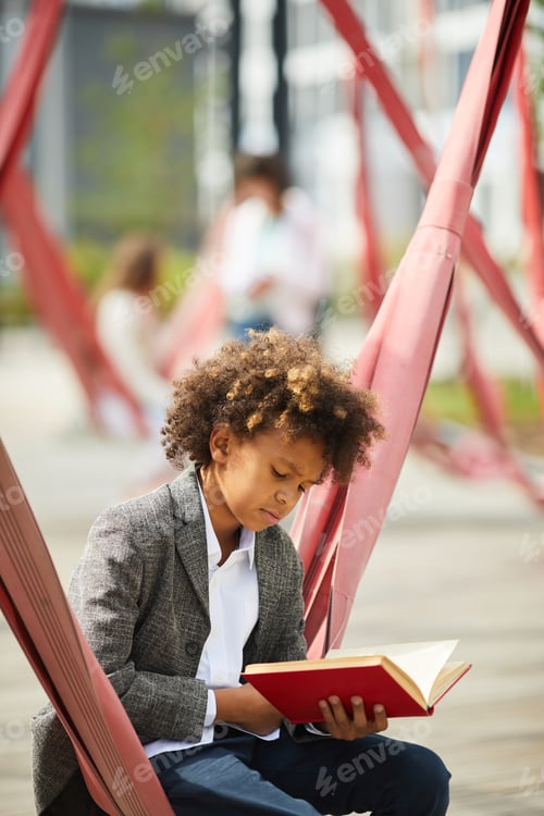 Preview: Schoolboy with book outdoors