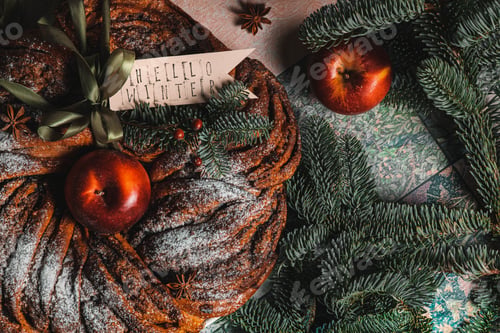 Preview: Cinnamon sugar round brioche with hole inside on the table decorated with apples and christmas toys