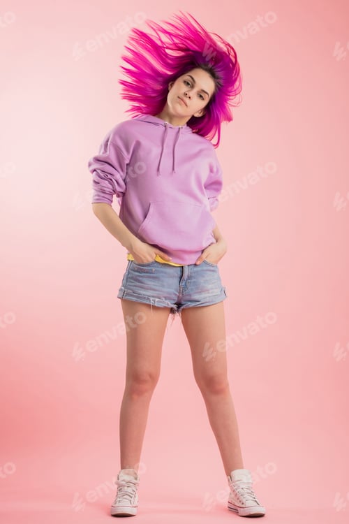 Preview: beautiful fashion girl with flying violet hair looking at camera over pink background.