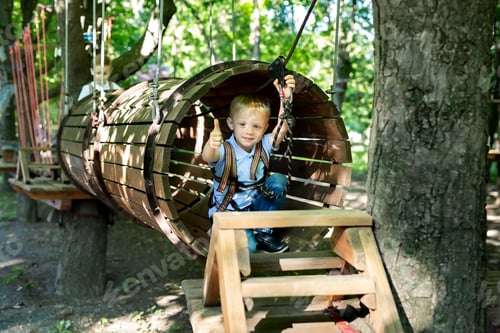 Preview: Little active boy who climbs on a rope the way to the amusement Park in the summer.