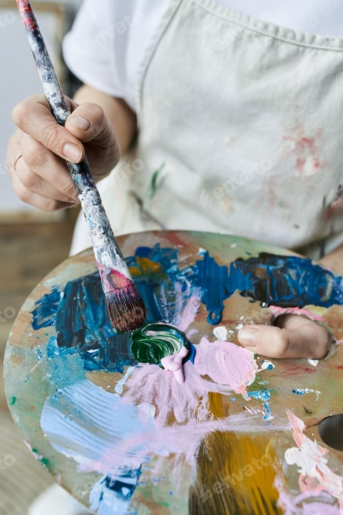 Preview: Mature woman expressing creativity in her vibrant art studio while painting