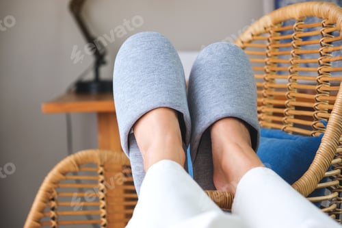 Preview: Closeup of a woman wearing slippers, laying and putting legs on wooden chair
