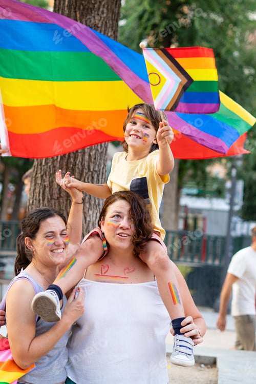 Preview: Happy family celebrating gay pride with rainbow flags and painted faces