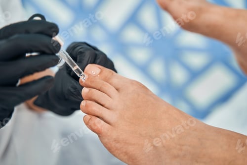Preview: Close up of specialist putting oil on nails