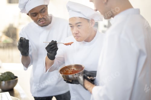 Preview: Chef cooks tasting sauce with a spoon while cooking in the kitchen