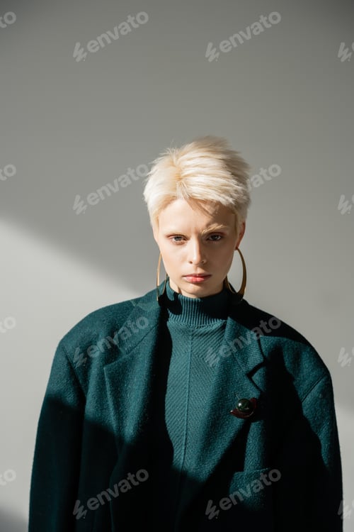 Preview: young albino woman with fair-skin posing in green dress and coat on grey background