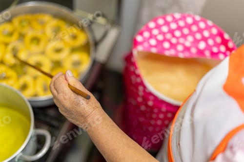 Preview: Woman cooking picarones, traditional peruvian dessert, using wooden stick