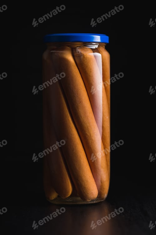 Preview: Tasty sausages. Preserved frankfurters in glass jar on black background.