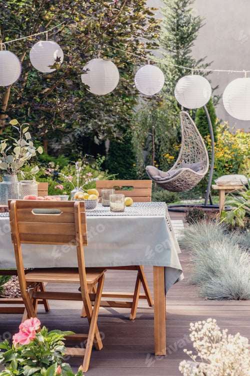 Preview: White paper lamps above garden table with chairs on stylish terrace with wooden floor and plants