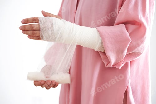 Preview: A woman in a pink shirt holds a bandage and puts a bandage on her arm.