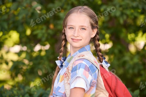 Preview: Smiling young caucasian girl with pigtails and backpack enjoying nature