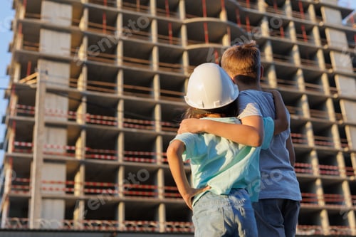 Preview: Children, a boy and a girl, are looking at the construction of a multi-storey building.