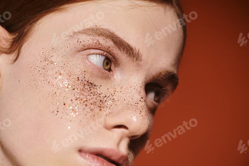 Preview: Stylish young queer man with long red hair showcases modern beauty against a warm backdrop