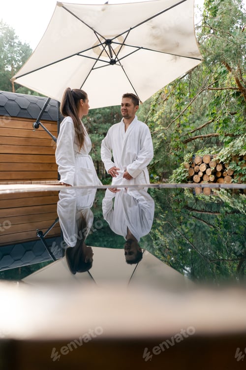 Preview: A young beautiful loving couple in dressing gowns prepare to swim in an outdoor pool in the woods