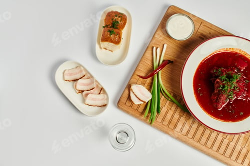 Preview: rich flavor Ukrainian borsch near garlic buns, pork lard and sour cream on wooden cutting board