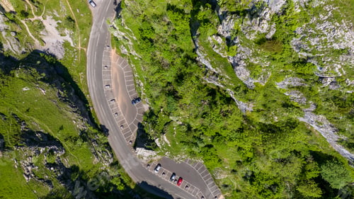 Preview: a mountain road with cars traveling down it near trees and cliffs