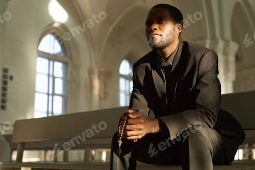 Preview: Black Man as Priest Holding Rosary in Church