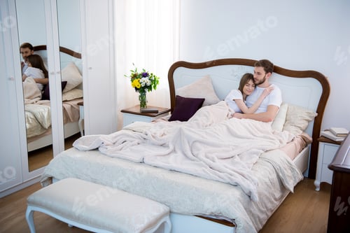 Preview: Couple lying on bed in cozy modern bedroom