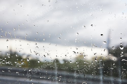 Preview: Raindrops on a window with a blurred cityscape in the background.