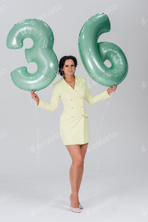 Preview: girl on a white background in a yellow dress green numbers 36 birthday balloons. holiday concept