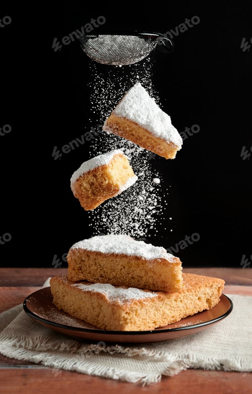 Preview: Sweet slices of cake falling onto plate with icing sugar being sprinkled on top