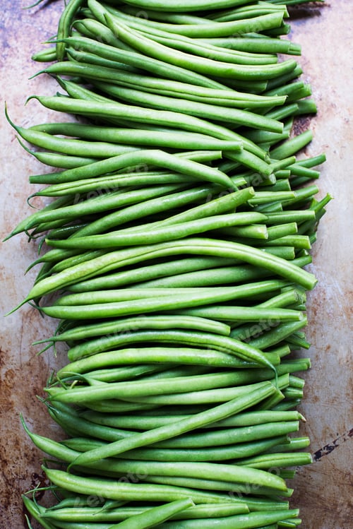 Preview: A neat array of fresh green beans on a rustic metal surface.