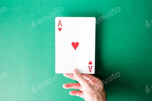 Preview: Hand holding a playing card on green background.