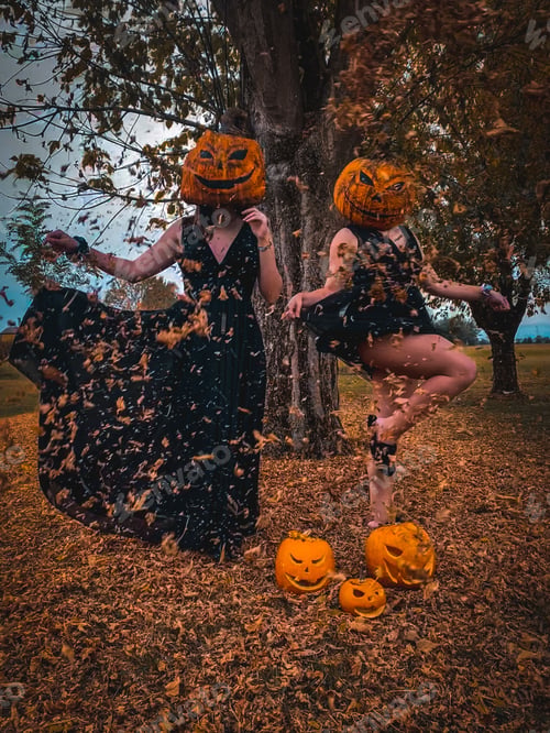 Preview: Female friends joyfully celebrating the Halloween season by jumping while wearing pumpkins