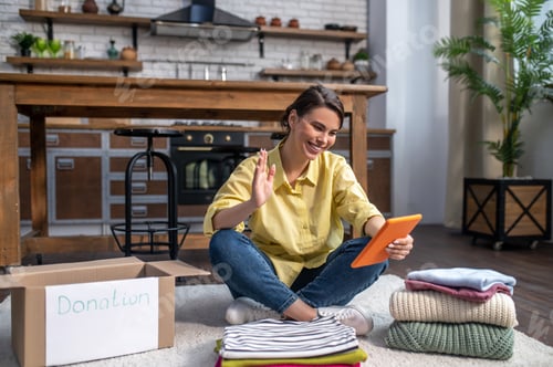 Preview: Joyful woman sitting on the floor and communicating over Skype