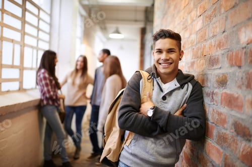 Preview: Portrait of a handsome young male student leaning against a wall with his friends in the background