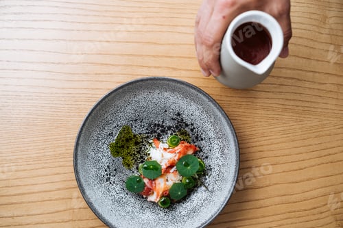 Preview: Hand pouring sauce into Nordic appetizer
