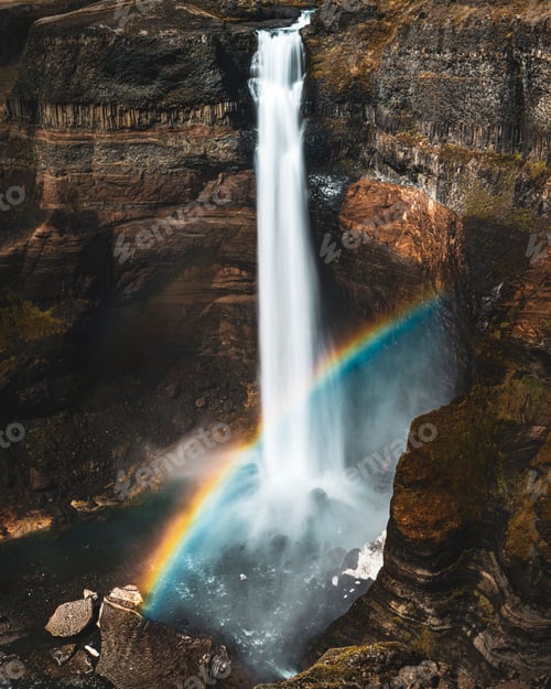 Preview: The landscape of Haifoss waterfall with a vivid rainbow arching above it.