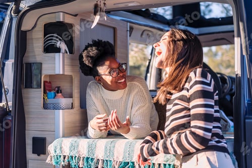 Preview: two women laughing in a conversation in camper van
