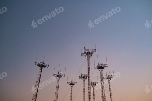 Preview: Low-angle shot of multiple antennas atop the towers against a sunset sky