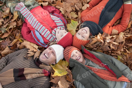 Preview: Family lying together in autumn leaves, laughing
