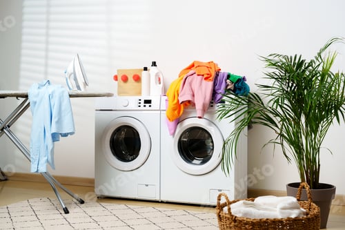 Preview: Modern Laundry Room With White Washing Machines, Ironing Board, and Houseplant
