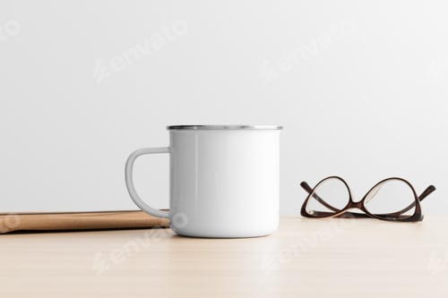 Preview: Enamel mug mockup with workspace accessories on the wooden table.